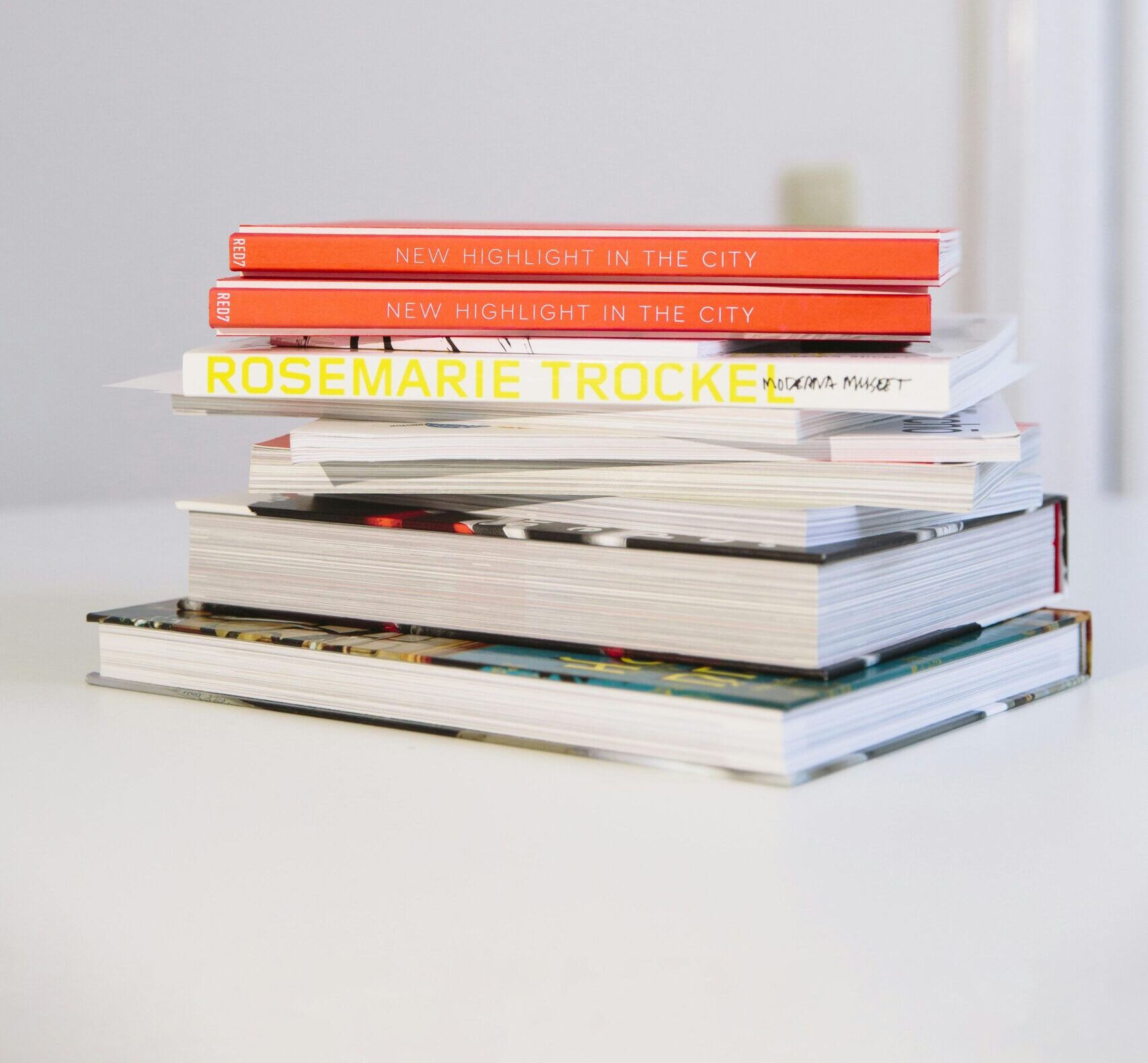 A neatly stacked pile of hardcover books on a white table.